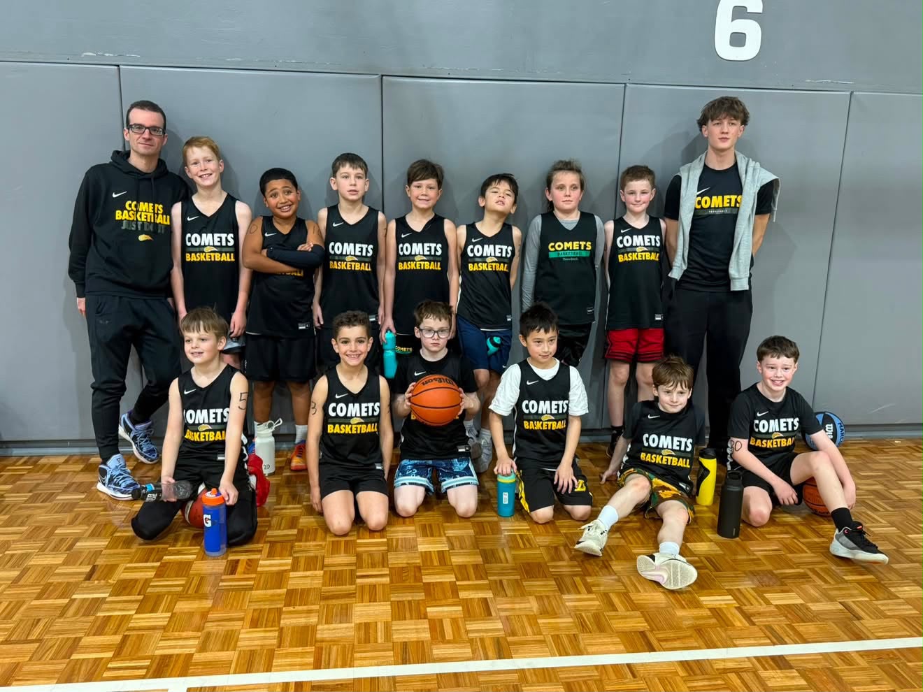 A group of fifteen youth basketball players standing together on the court wearing their official Sydney representative basketball uniforms.